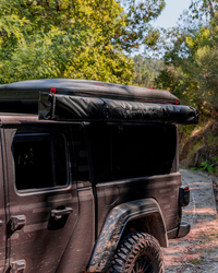 James Baroud Hartschalen-Dachzelt Odyssey Magma montiert auf einem Hardtop auf einem Offroad-Fahrzeug. Dachzelt ist eingeklappt. Mit Montierter Markise an der Seite.
