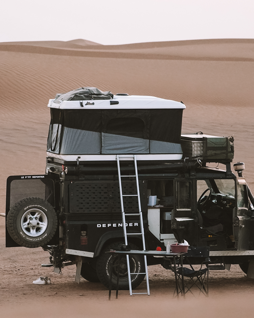 James Baroud Hartschalen-Dachzelt Grand Raid schwarz montiert auf einem Offroad-Fahrzeug. Dachzelt ist aufgebaut. Mit Leiter Zustieg. Gepäck auf dem Dach.