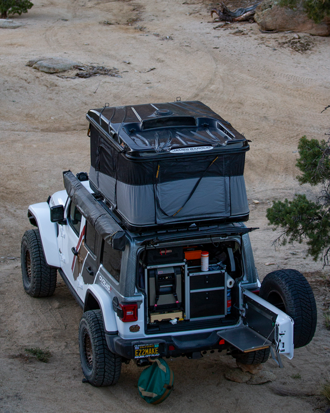 James Baroud Hartschalen-Dachzelt Grand Raid schwarz montiert auf einem Offroad-Fahrzeug. Dachzelt ist aufgebaut. Markise wurde befestigt am Dachzelt.