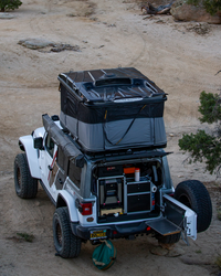 James Baroud Hartschalen-Dachzelt Grand Raid schwarz montiert auf einem Offroad-Fahrzeug. Dachzelt ist aufgebaut. Markise wurde befestigt am Dachzelt.
