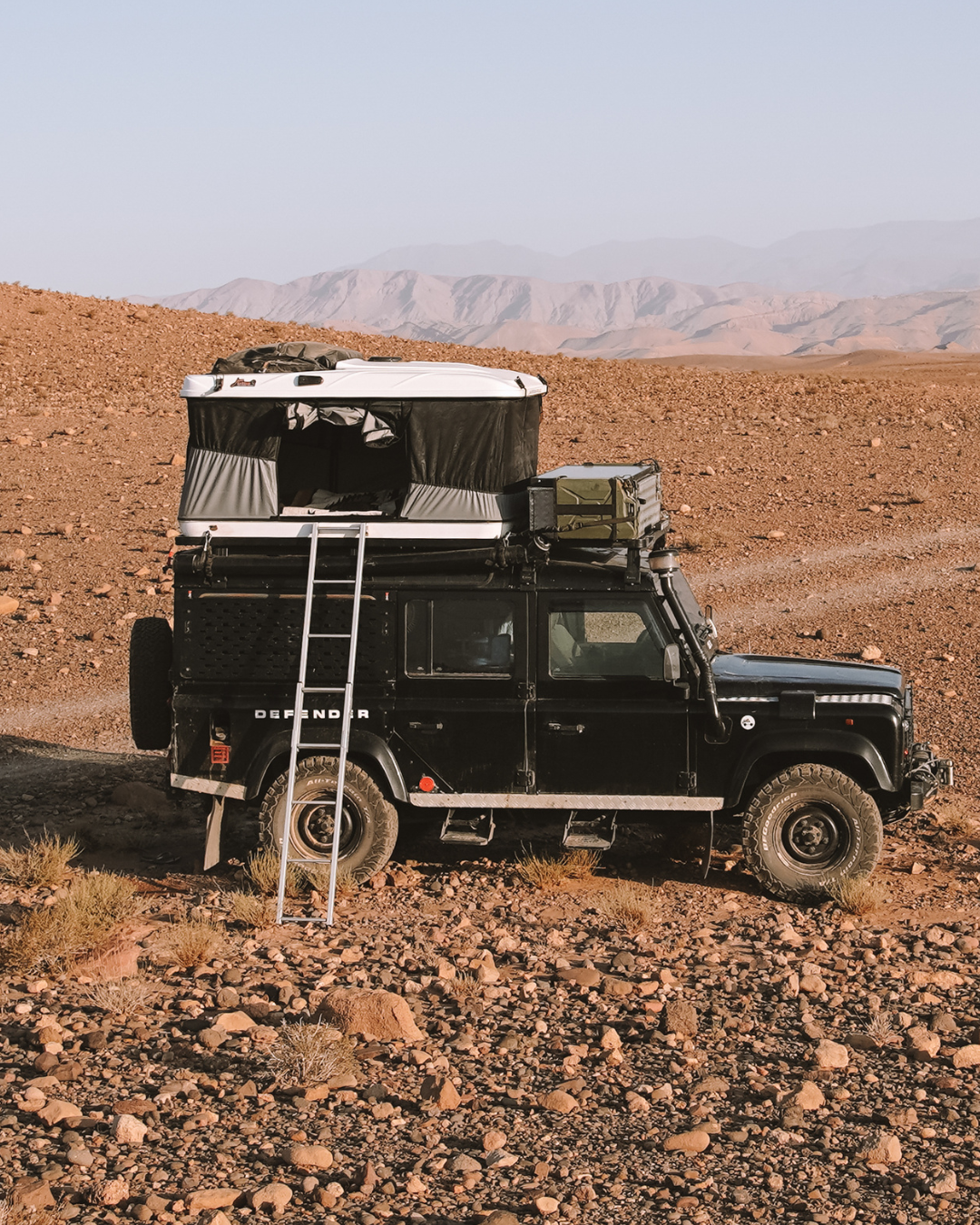 James Baroud Hartschalen-Dachzelt Grand Raid schwarz montiert auf einem Offroad-Fahrzeug. Dachzelt ist aufgebaut. Mit Leiter Zustieg.