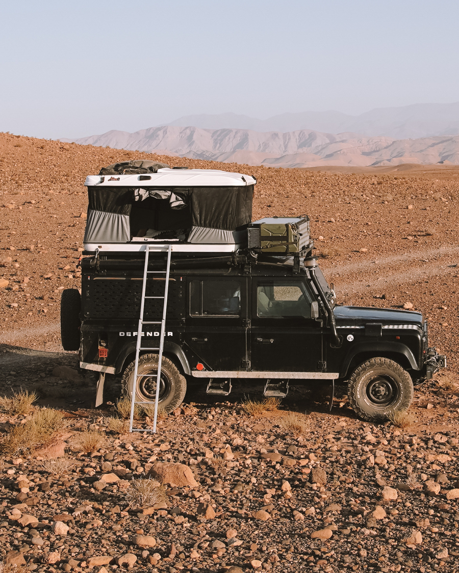James Baroud Hartschalen-Dachzelt Grand Raid schwarz montiert auf einem Offroad-Fahrzeug. Dachzelt ist aufgebaut. Mit Leiter Zustieg.