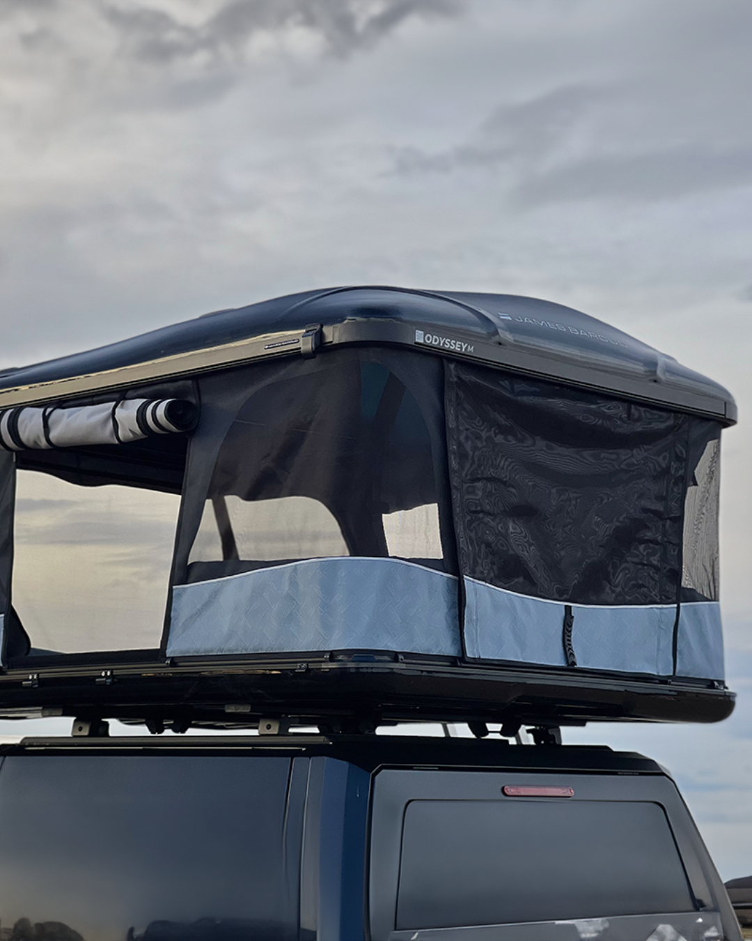 James Baroud Hartschalen-Dachzelt Odyssey schwarz montiert auf einem Offroad-Fahrzeug. Dachzelt ist offen.