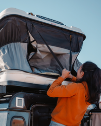 James Baroud Hartschalen-Dachzelt Grand Raid schwarz montiert auf einem Offroad-Fahrzeug. Dachzelt wird eingeklappt. Gurt zum runterziehen.
