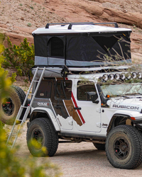 James Baroud Hartschalen-Dachzelt Odyssey weiß montiert auf einem Offroad-Fahrzeug. Dachzelt ist offen. Leiter steht an offenem Eingang.