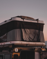 James Baroud Hartschalen-Dachzelt Grand Raid schwarz montiert auf einem Offroad-Fahrzeug. Dachzelt ist aufgebaut. Gepack auf dem Dach.
