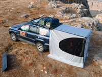 Aufgebaute Markise mit Seitenwänden und geöffnetem Fenster an einem Offroad-Fahrzeug. Montiert am Heck des Autos.