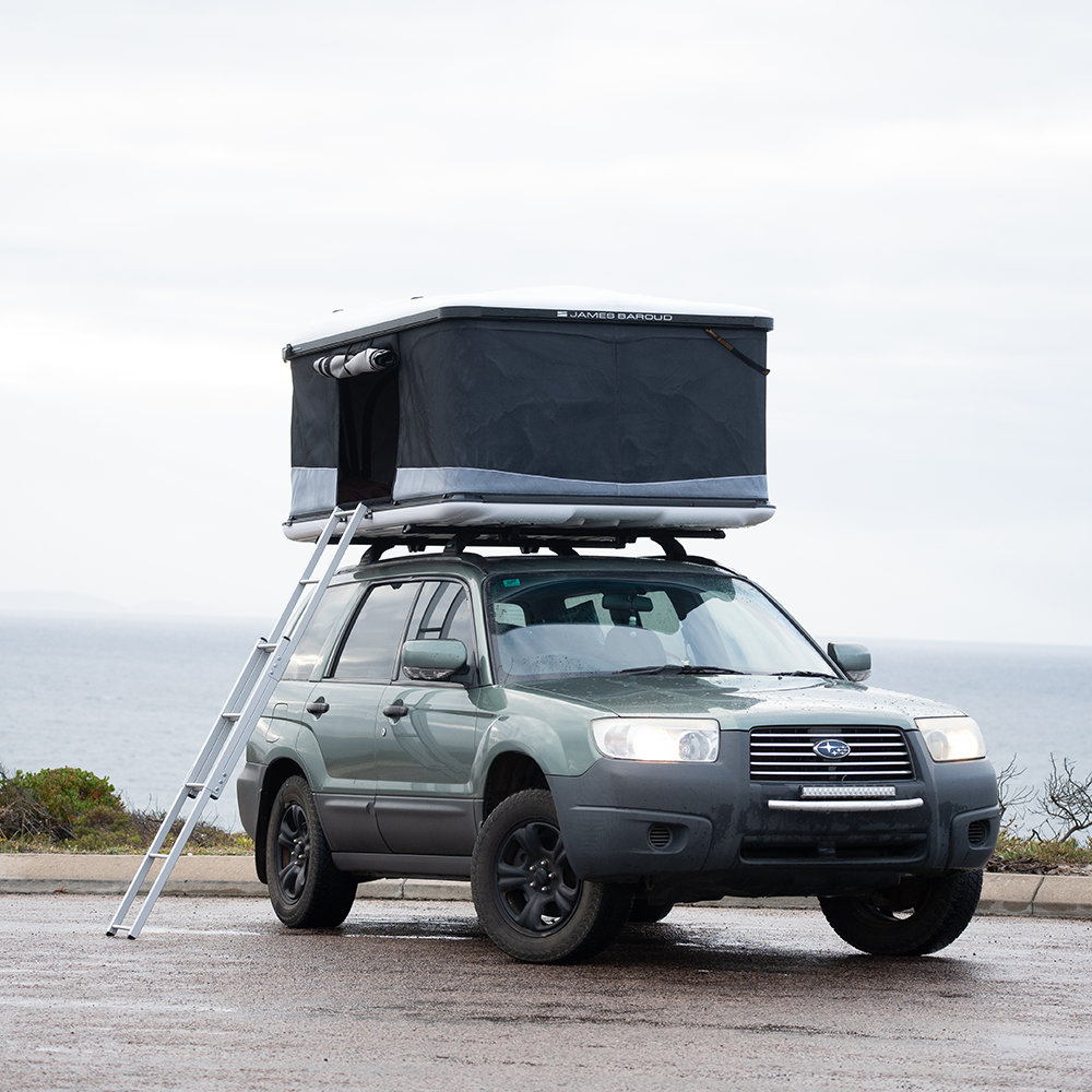 James Baroud Hartschalen-Dachzelt  Odyssey Weiß montiert auf einem Offroad-Fahrzeug Offen, mit Leiter zugänglich.
